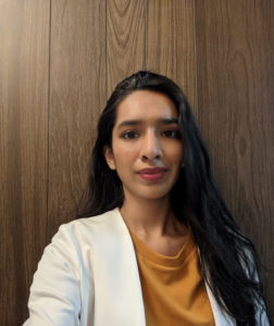 A headshot of ECLP member Aishwarya Kothari in an orange shirt and white blazer